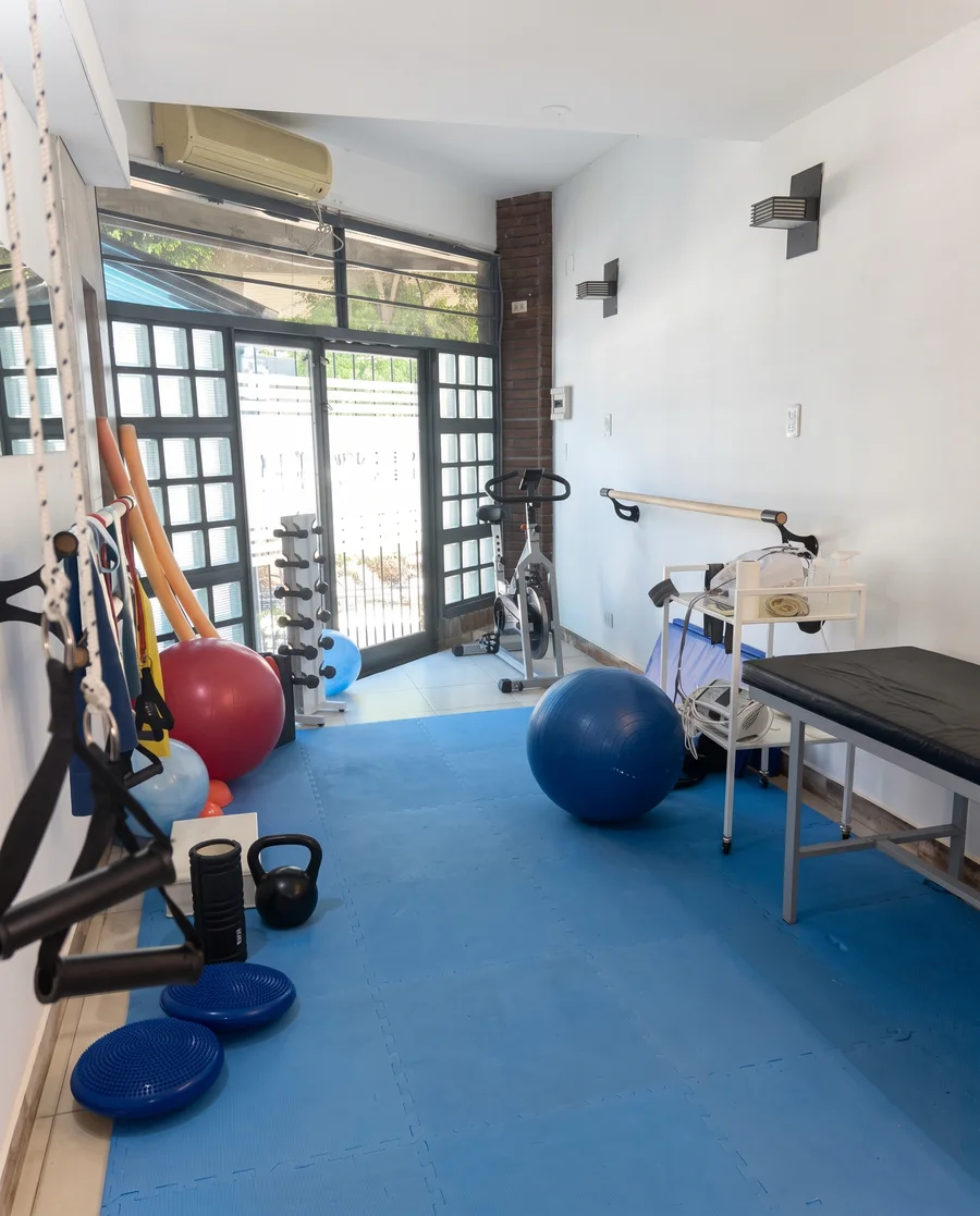 Gimnasio de rehabilitación con colchonetas, pelotas y bicicleta